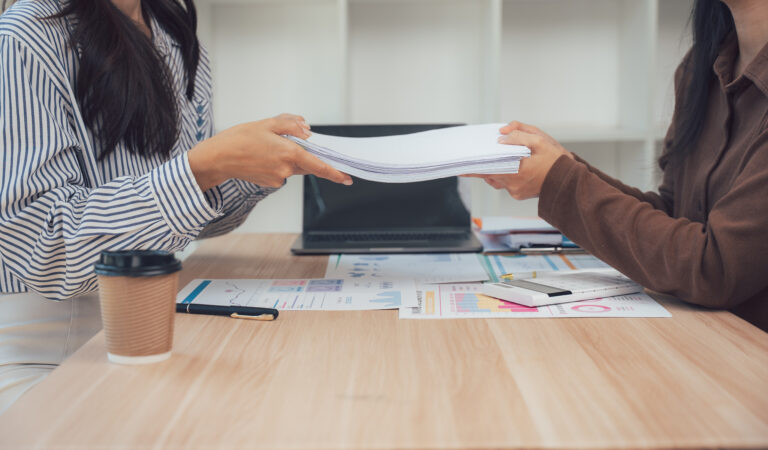 Handing Over: A collaborative office scene as one individual hands over documents to another, fostering seamless teamwork and efficient communication.