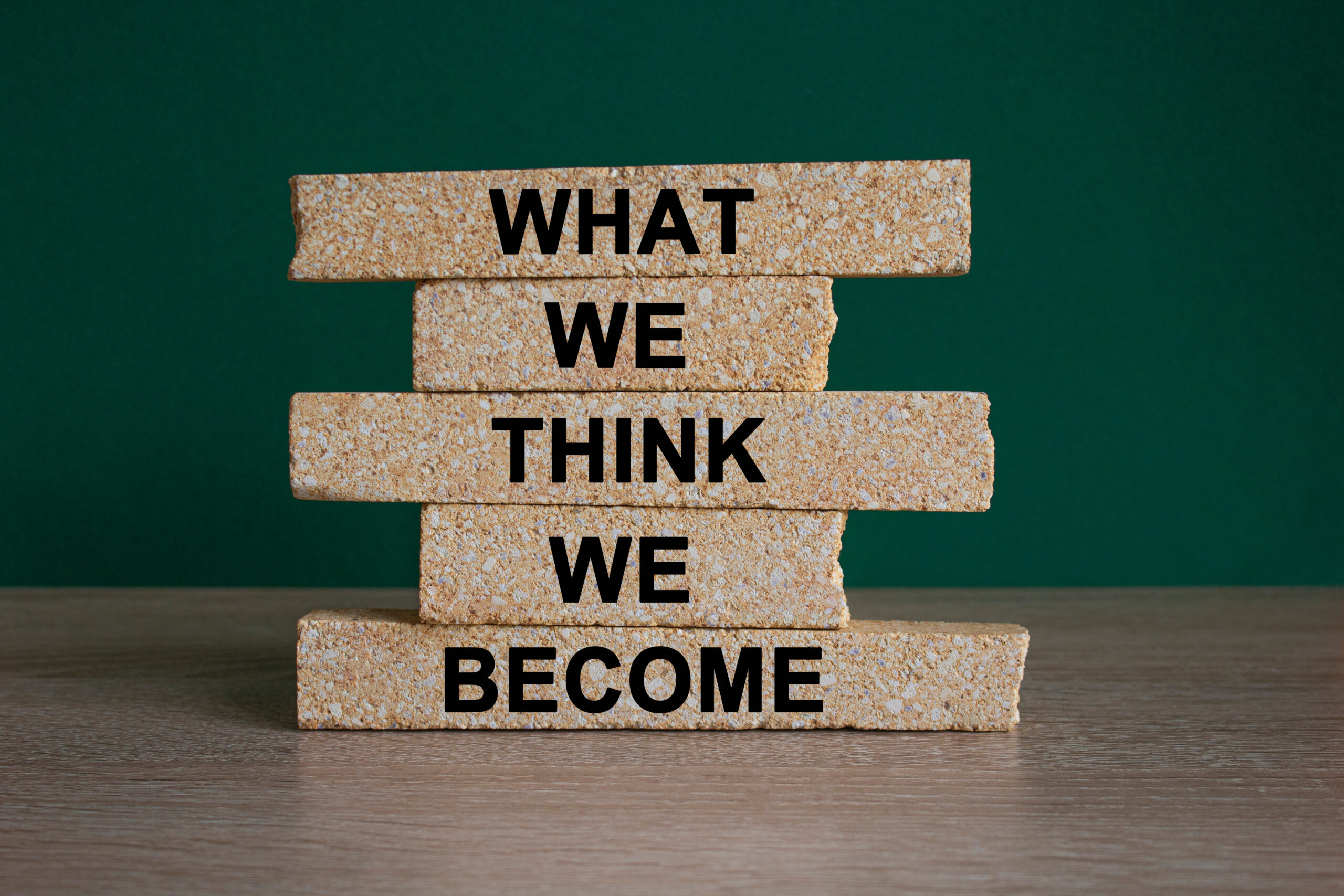 We become or think symbol. Concept word What we think We become on brick blocks. Beautiful wooden table, green background. Business we become or think concept. Copy space.
