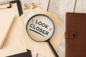 Look Closer Concept with Magnifying Glass Over Envelope on Office Desk