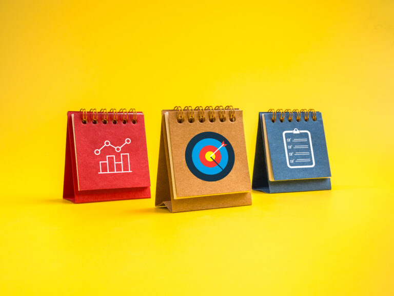 Three colorful standing calendars on yellow background showing data chart, target goal, and checklist icons, representing business action plan, strategic planning, and productivity concept.