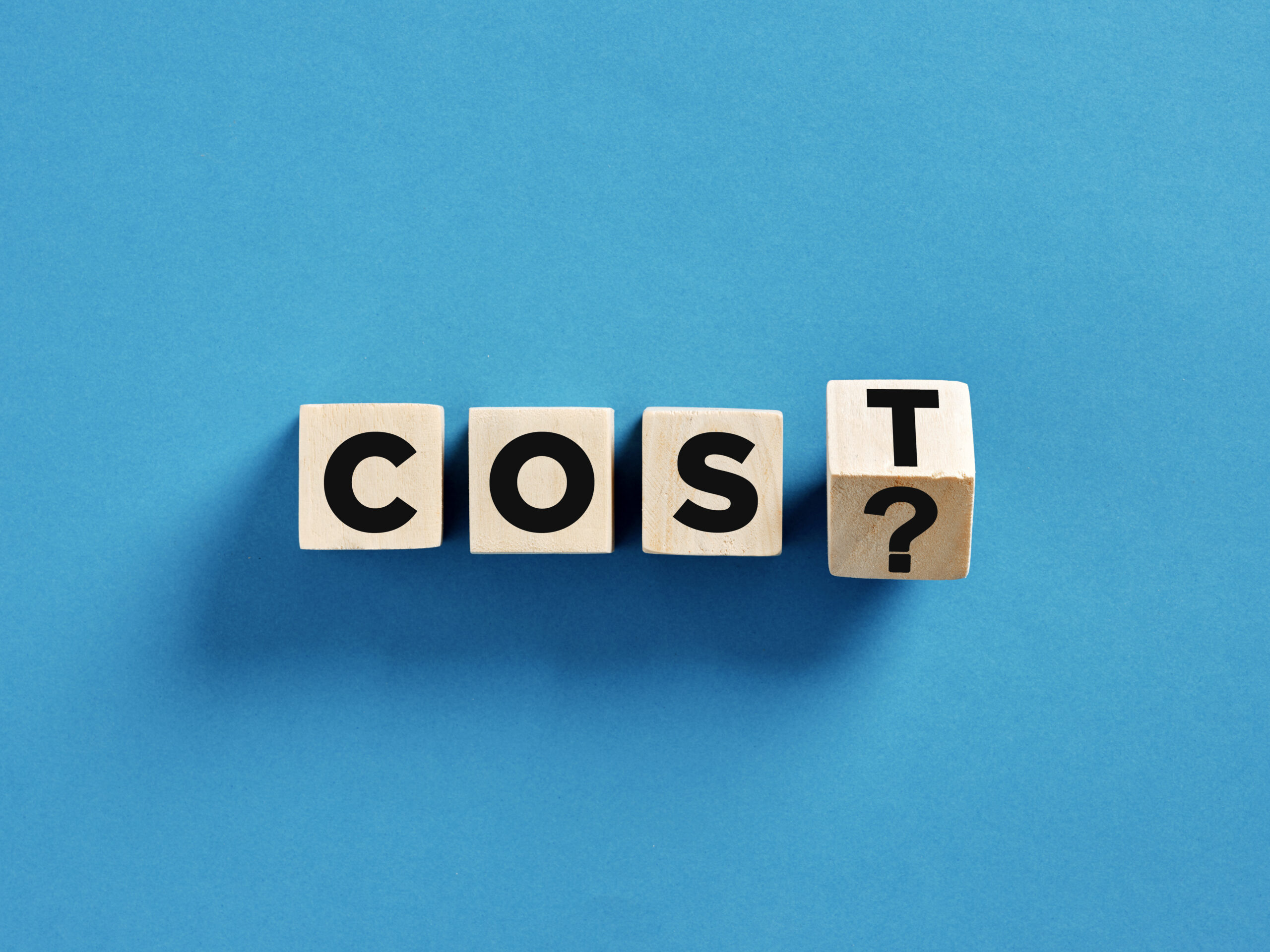 Asking the real cost question using wooden cubes on blue background