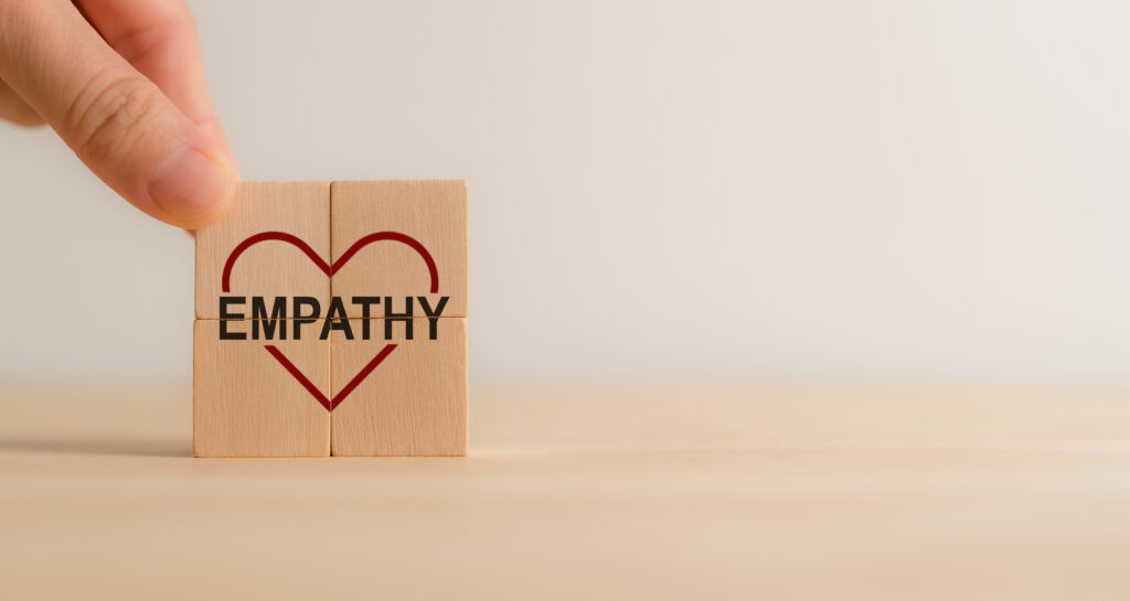Empathy concept. Wooden blocks with empathy icons on minimal background and copy space. The power of emotional intelligent, soft skill development. Empathy in the workplace, good leaders, good teams.
