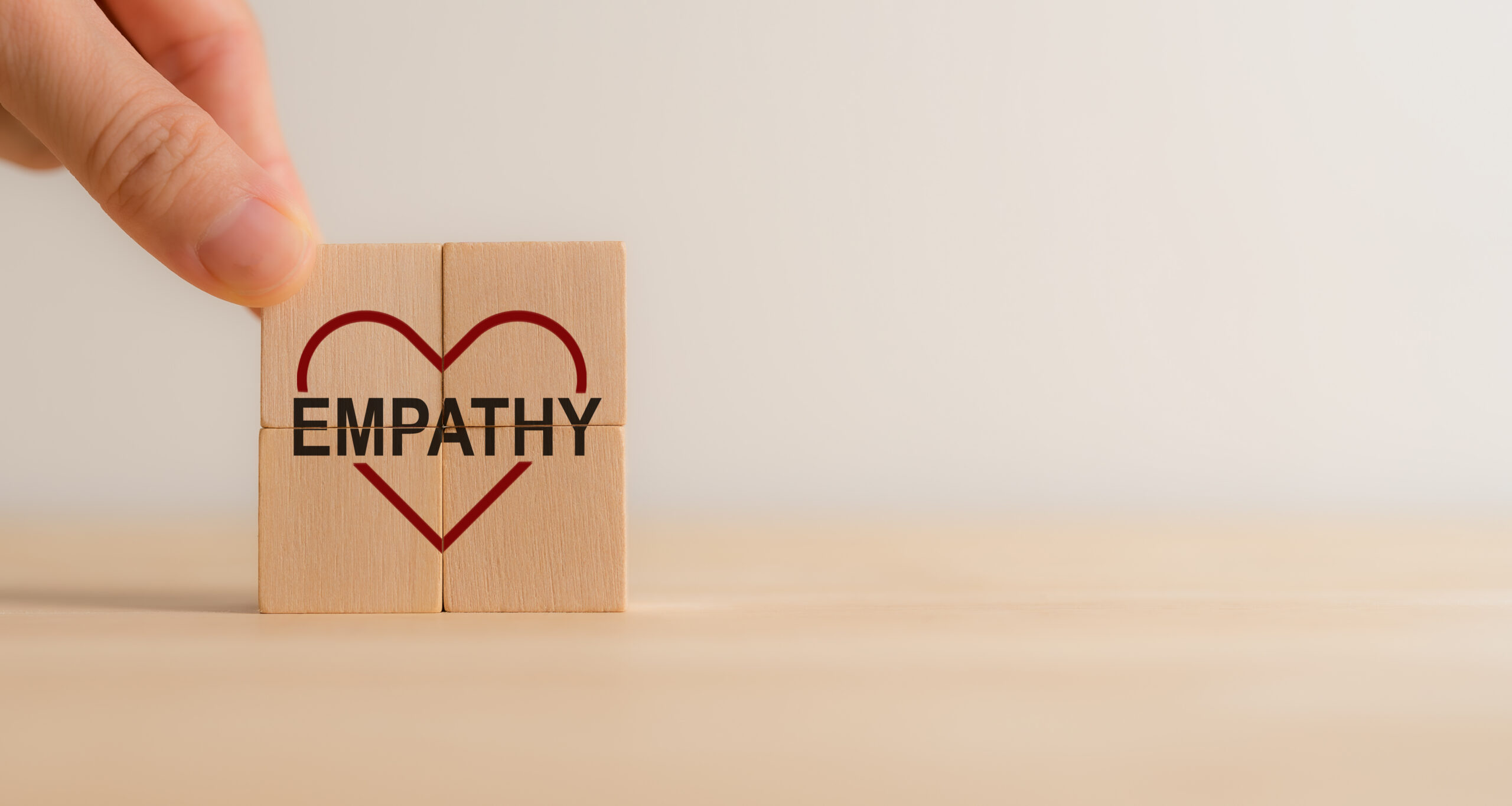 Empathy concept. Wooden blocks with empathy icons on minimal background and copy space. The power of emotional intelligent, soft skill development. Empathy in the workplace, good leaders, good teams.