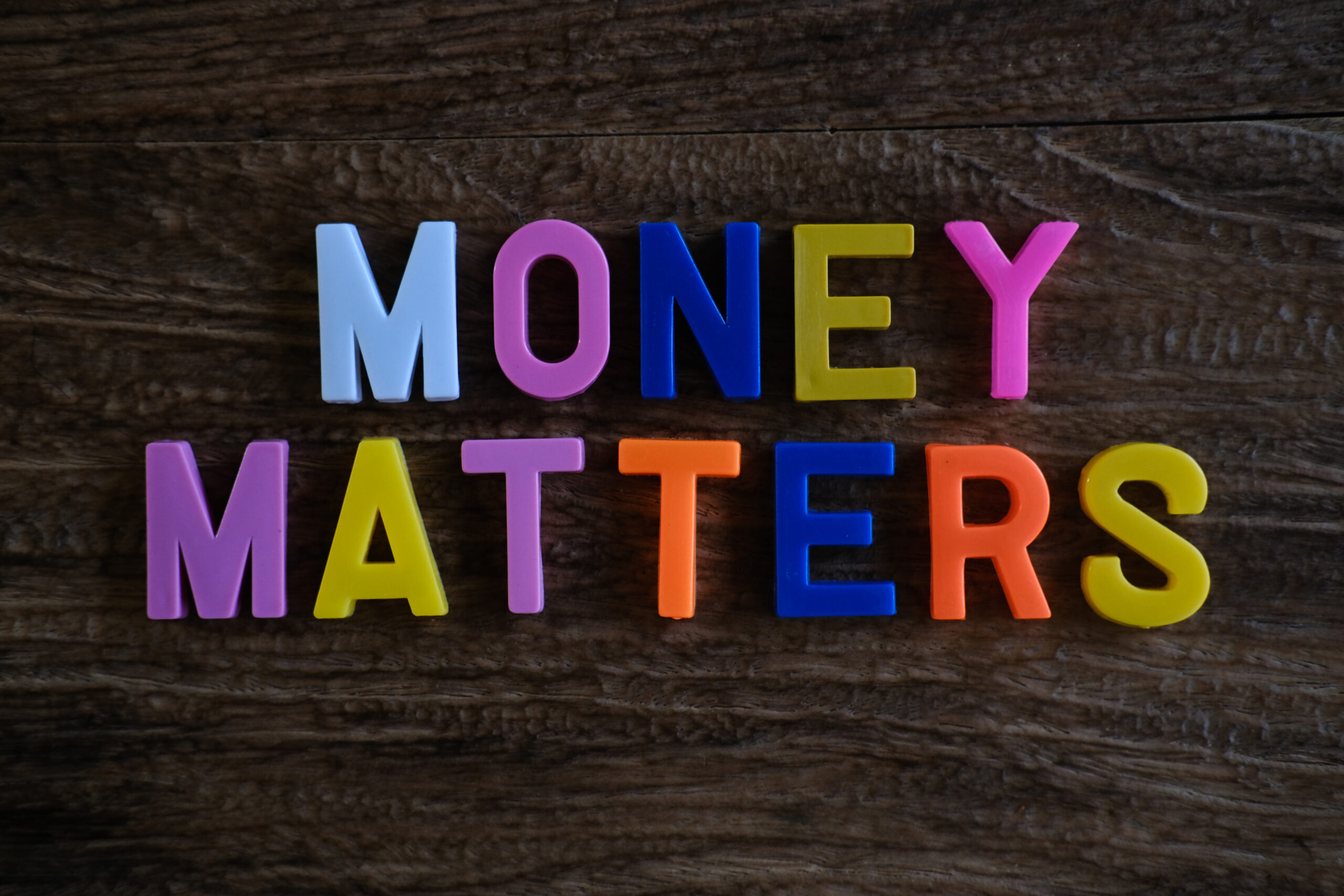 Money Matters Words Made from Colorful Plastic Alphabet Letters on Dark Textured Wooden Background with Copy Space
