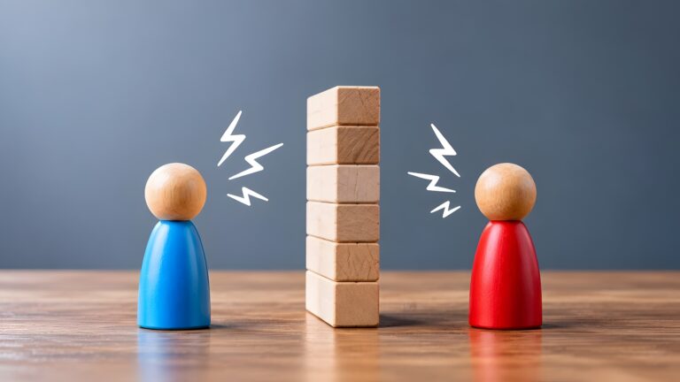 Two wooden figures separated by a block wall with lightning symbols representing workplace conflict and communication barriers
